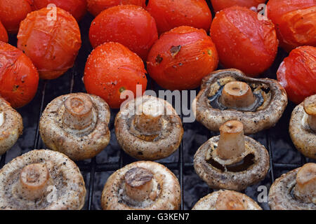 Dans les légumes de sel, d'épices et de la cuisson sur gril char, blanc champignons portobellos et petites tomates rouges Banque D'Images