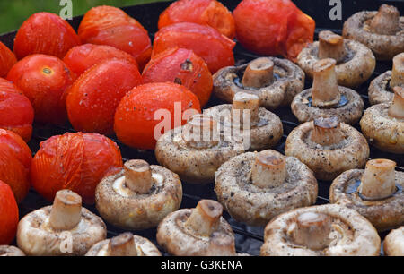 Dans les légumes de sel, d'épices et de la cuisson sur gril char, blanc champignons portobellos et petites tomates rouges Banque D'Images