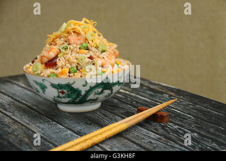 Riz frit à la chinoise cuisinés avec de la saucisse chinoise, crevettes, oeuf, petits pois et l'oignon vert. Servi sur du riz chinois vintage bol. Banque D'Images