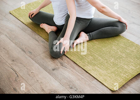 Gros plan du slim deux jeunes femmes pratiquant le yoga sur le tapis vert en studio Banque D'Images