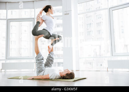 Jeune homme concentré et woman doing yoga acro pour les couples en studio Banque D'Images