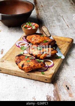 Cuisses de poulet tandoori grillées avec salade sur planche à découper Banque D'Images