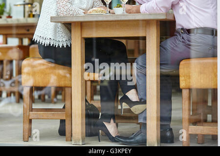 Taille vers le bas de la chaussure haut talon womans mans toucher jambe à table de restaurant Banque D'Images