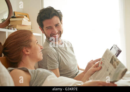 Couple reading [affiche et digital tablet in bed Banque D'Images