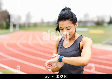 Jeune femme sur une piste de course, contrôle de regarder Banque D'Images