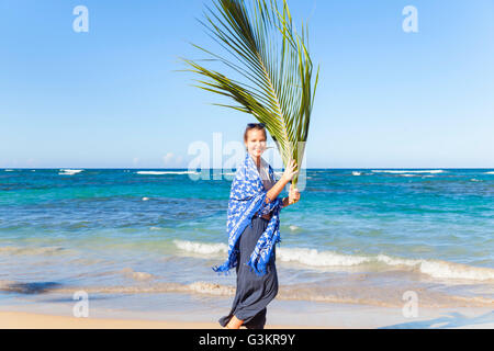 Portrait de jeune femme portant la feuille de palmier sur la plage, la République dominicaine, les Caraïbes Banque D'Images