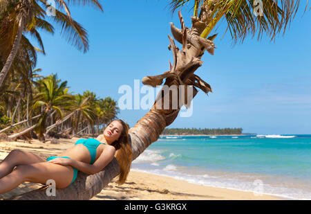 Young woman wearing bikini sunbathing on palm tree, la République dominicaine, les Caraïbes Banque D'Images