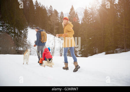 Vue arrière des parents tirant fils sur toboggan dans la neige paysage, Elmau, Bavière, Allemagne Banque D'Images