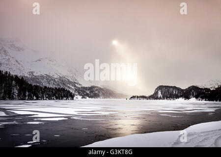 Rayons de soleil qui brille sur le lac et montagnes couvertes de neige, Engadine, Suisse Banque D'Images