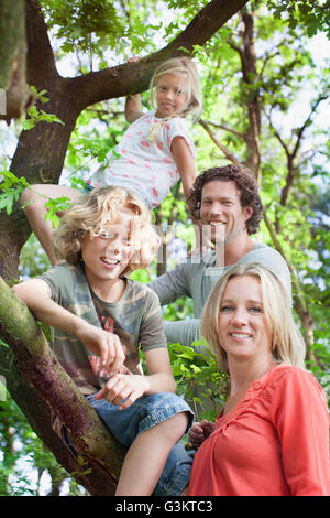 Dans la famille forest climbing tree looking at camera smiling Banque D'Images