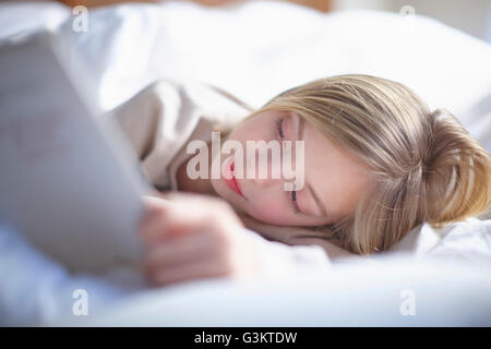 Fille d'une chevelure blonde dans mon lit en lisant un livre Banque D'Images