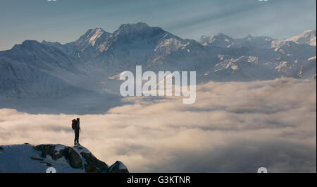 Grimpeur sur un pic émergeant de brouillard dans les Alpes, Bettmeralp, Valais, Suisse Banque D'Images