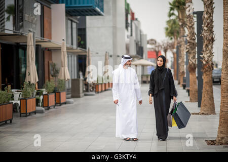 Middle Eastern shopping couple portant des vêtements traditionnels carrying shopping bags, Dubaï, Émirats Arabes Unis Banque D'Images