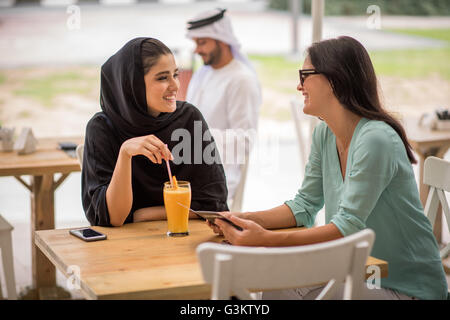 Les jeunes middle eastern woman wearing vêtements traditionnels parler avec amie au café, Dubaï, Émirats Arabes Unis Banque D'Images