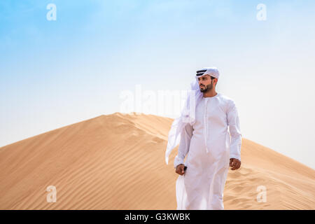 Middle Eastern homme portant des vêtements traditionnels sur les dunes du désert, Dubaï, Émirats Arabes Unis Banque D'Images