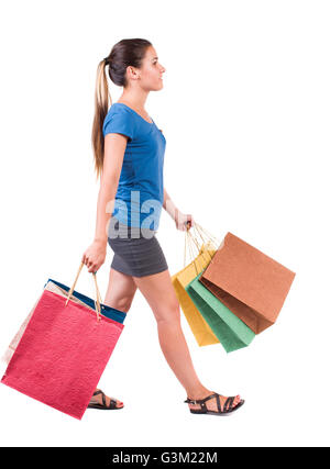 Vue arrière d'aller woman with shopping bags . belle fille de motion. dos vue de personne. Vue arrière personnes collection. Plus isolé sur fond blanc. Fille dans une jupe gris et bleu T-shirt porte sacs. Banque D'Images