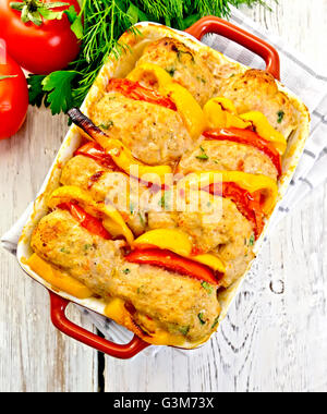 Les escalopes de dindon cuite au four avec tomates et poivron jaune dans une plaque à rôtir sur une serviette, le persil sur l'arrière-plan lig Banque D'Images