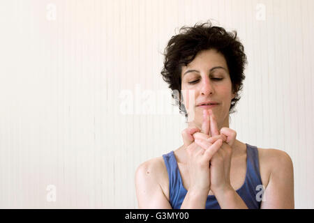 Femme pratiquant de yoga l'exécution d'un Devi mudra (position de la main) dans le studio Banque D'Images