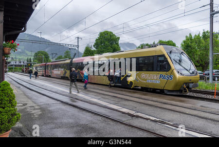 Les passagers d'un train de la ligne GoldenPass Panoramic MOB Montreux / Gstaad bernois de fer sur un jour de pluie. Saanen, Suisse. Banque D'Images