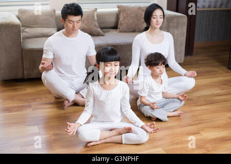 Jeune famille faisant du yoga à la maison Banque D'Images