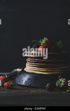 Crêpes au chocolat dans la casserole rouillée avec les fruits comme les fraises et les mûres sur la vieille table en bois Banque D'Images