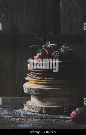 Rustique, avec des crêpes au chocolat fruits comme les fraises et les mûres sur des blocs de bois avec les vieilles portes en bois à l'arrière Banque D'Images