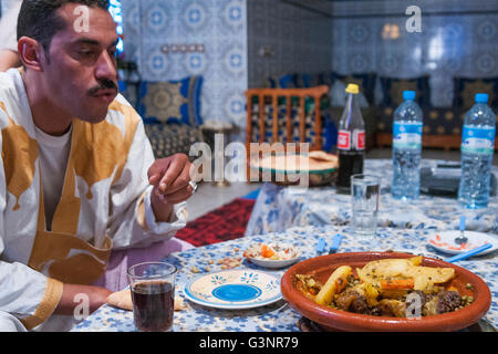 Un homme mange marocain tangine traditionnel repas à la maison décorée de carrelage bleu et blanc, Merzouga, Maroc, Afrique Banque D'Images