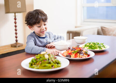 Petit garçon assis à la table à manger Banque D'Images