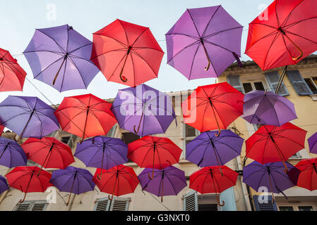 Des parasols colorés suspendus décoratifs entre les maisons d'une rue Banque D'Images