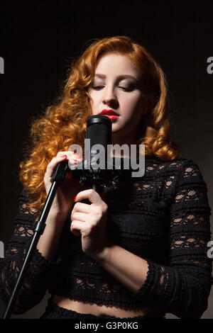 Portrait de la chanteuse aux cheveux bouclés avec des lèvres rouge mic holding Banque D'Images