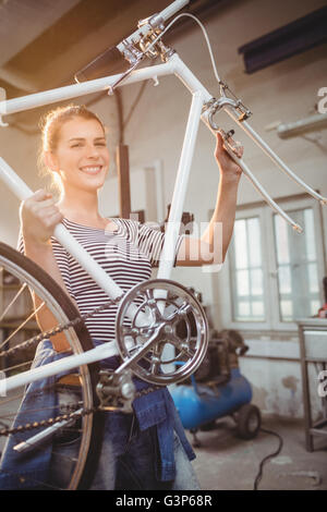 Femme tenant une bicyclette sans la roue avant Banque D'Images