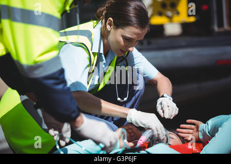 Équipe d'ambulanciers en prenant soin de femme blessée Banque D'Images