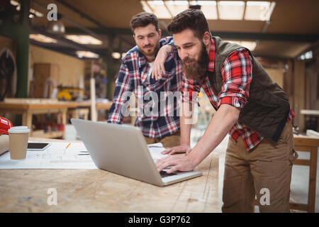 Carpenter using laptop tout en travaillant sur un plan Banque D'Images