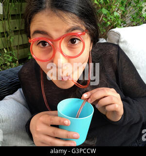 Adolescente de boire de la limonade avec un drôle de paille dans la forme de lunettes Banque D'Images