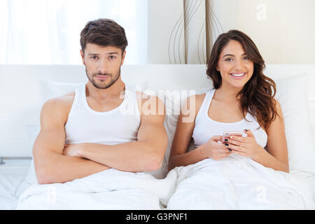 Jeune homme en colère couchée sur le lit avec une femme à la maison Banque D'Images