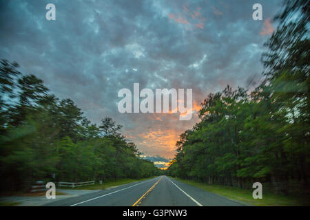 Coucher du soleil brillant dans la distance tandis que sur une autoroute à deux voies dans East Hampton, NY Banque D'Images