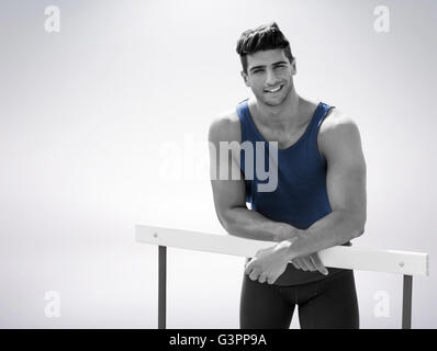 Portrait de sportif est souriant et posant sur un obstacle Banque D'Images