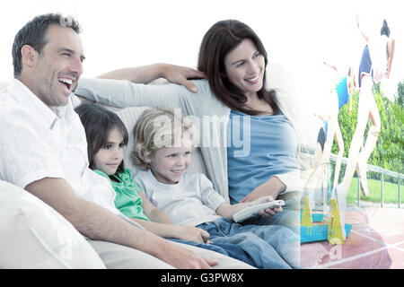 Image composite de l'heureuse famille regardent la télévision ensemble Banque D'Images