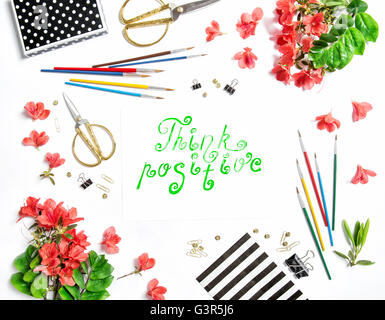 Mise à plat avec sketchbook, fleurs, fournitures de bureau sur fond blanc. Quote Pensez positif Banque D'Images
