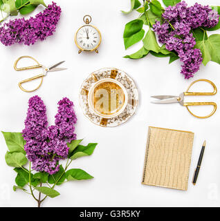 Fleurs lilas, journal notebook, tasse de café, golden de fournitures de bureau. Mise à plat Banque D'Images