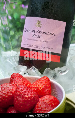 English Sparkling Rosé bouteille de vin en vin glacé refroidisseur avec bol de fraises fraîches sur la table de pique-nique en plein air Banque D'Images