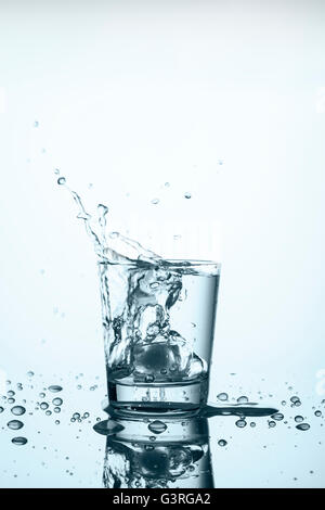 Ice Cube de tomber dans le verre avec de l'eau Banque D'Images