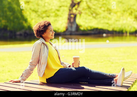 Happy african femme boit du café au parc d'été Banque D'Images