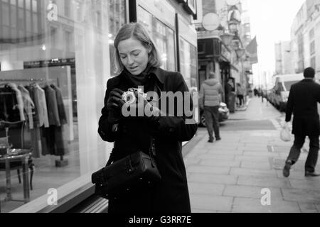 Dame élégante avec vintage Leica Camera taking photograph in Dover Street, Mayfair, Londres. Banque D'Images