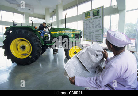 INDE, Maharashtra, Pune, concessionnaire de tracteurs John Deere dans le village, tracteur John Deere 5310 dans la salle d'exposition, agriculteur avec journal , son fils jouant sur le tracteur Banque D'Images