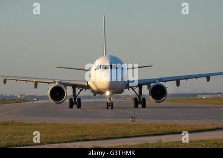 Avion de passagers circulant le long de la piste sur le coucher du soleil Banque D'Images