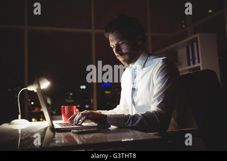 Businessman using laptop at night Banque D'Images