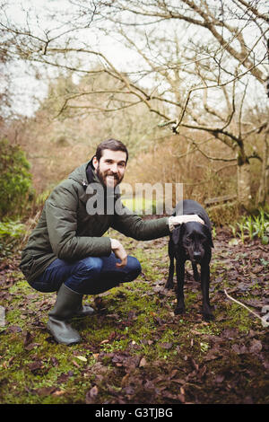 Hipster man smiling at camera tout en caressant son chien Banque D'Images