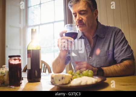 Young man sitting at table et dégustation de vin rouge Banque D'Images