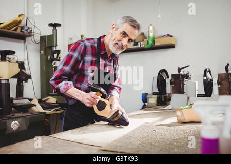 Cordonnier de sourire et de martelage sur le talon d'une chaussure Banque D'Images